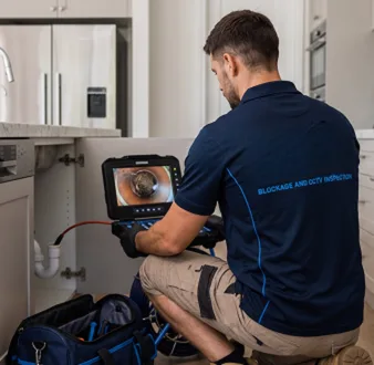 Plumber clearing a blocked toilet in a East Hills bathroom
